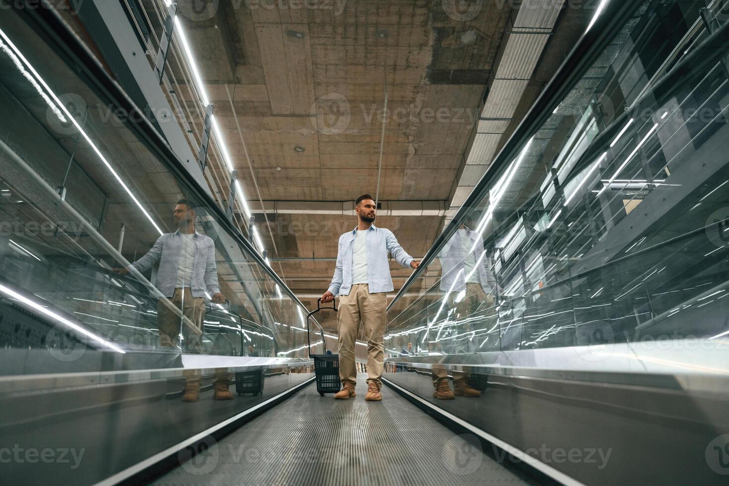Front,view. Handsome,,, man is on the escalator in the mall photo