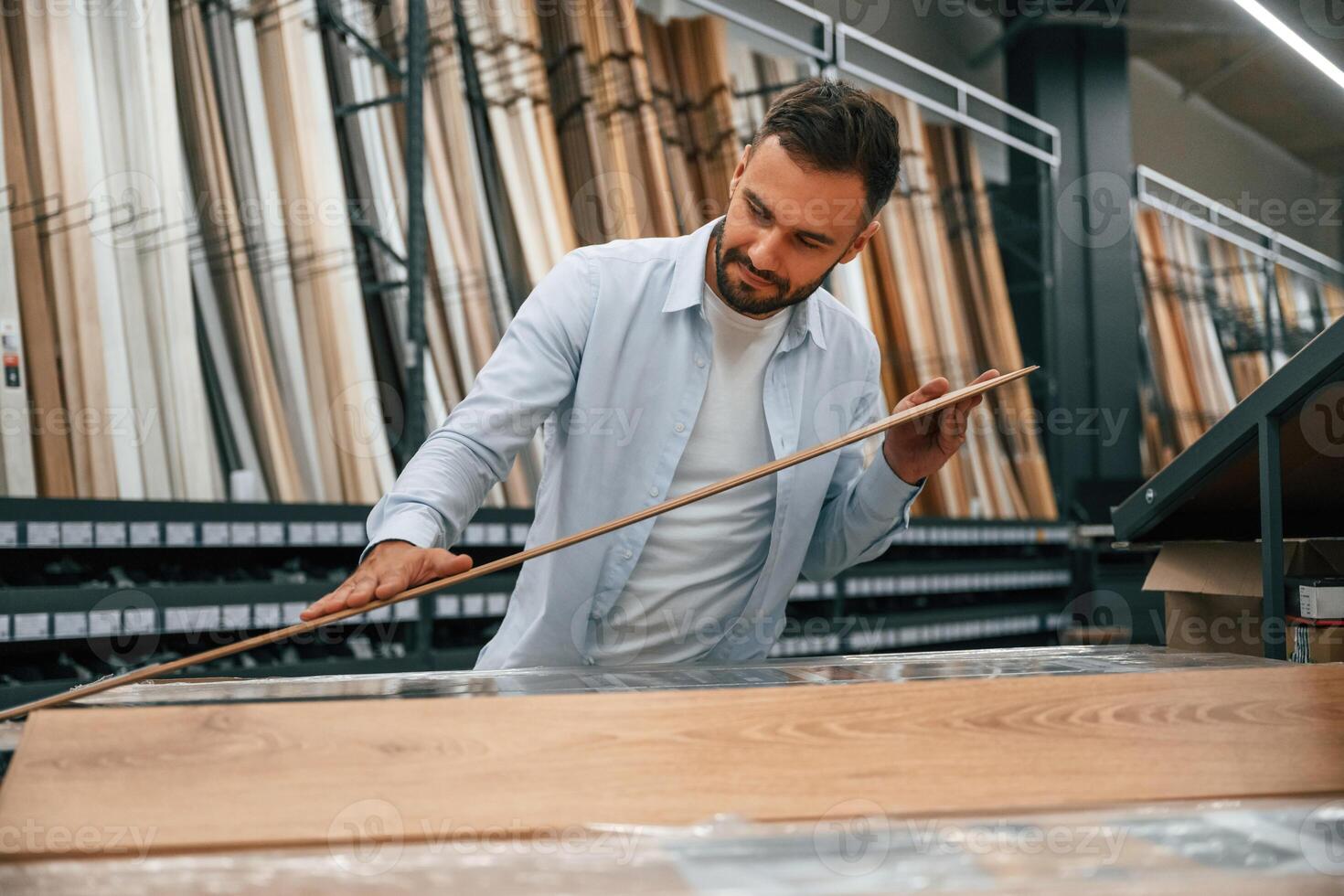 Quality ,of the, wood in parquet, checking. Man is in the hardware shop photo