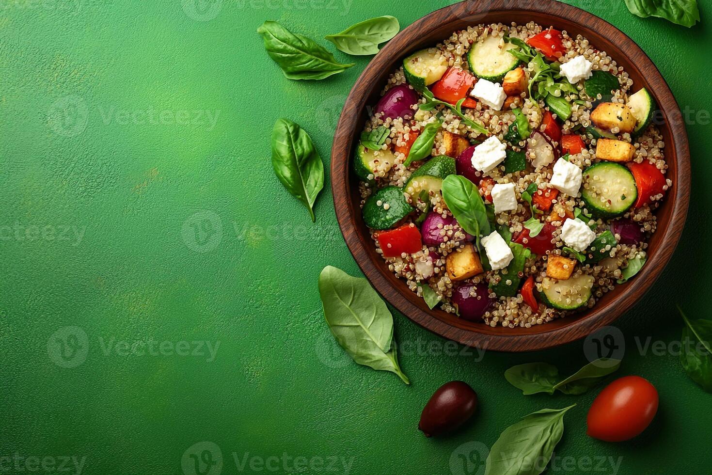 Quinoa salad with vegetables and feta cheese on a green background top view photo