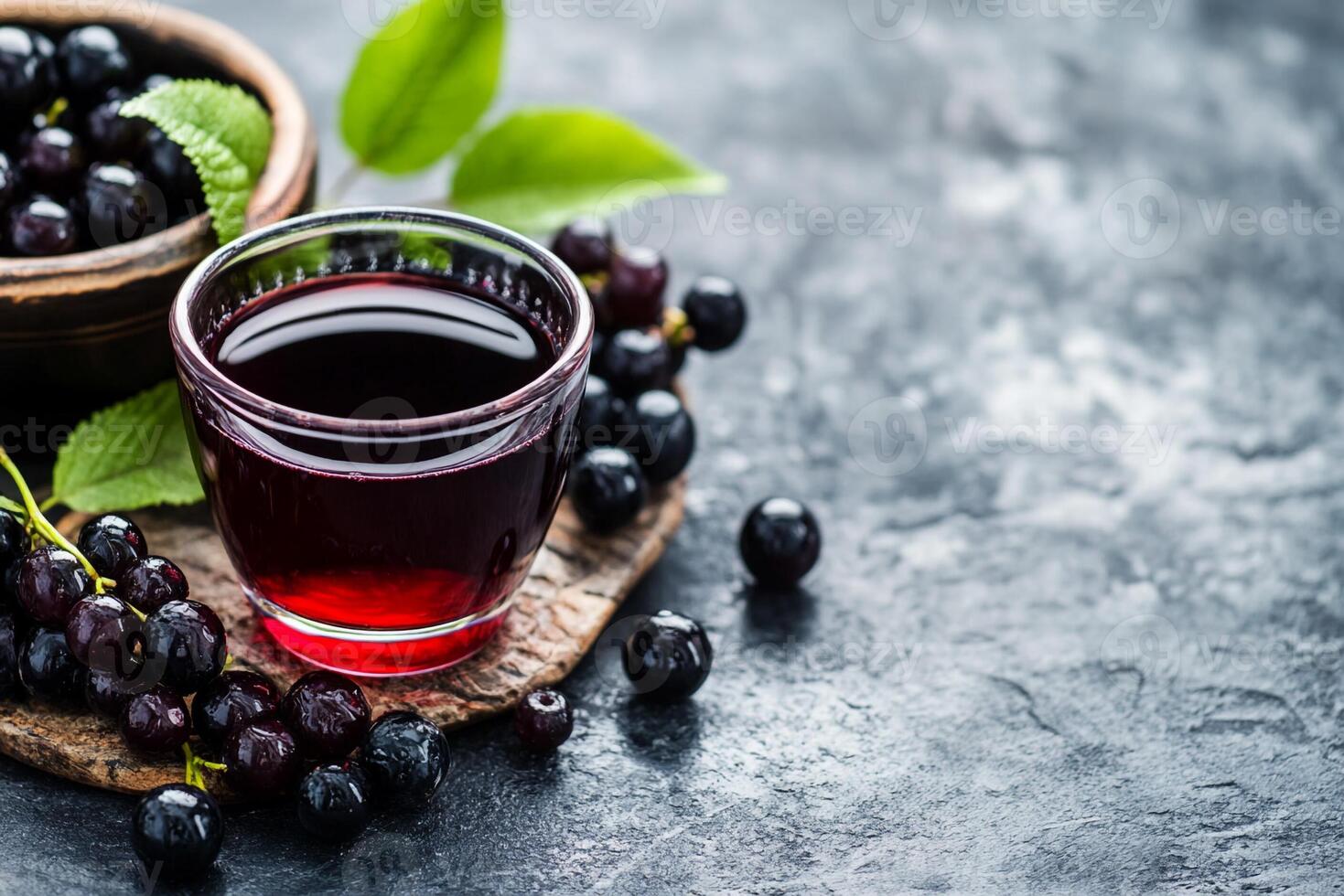 Black currant juice with black currant leaves and berries on a dark background photo