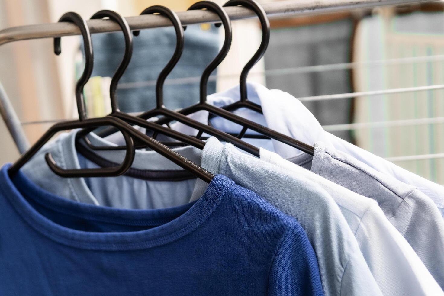 Soft blue and white shirts hanging neatly on black hangers in a gentle color gradient capturing the laundry aesthetic and minimal wardrobe organization in natural soft morning light photo