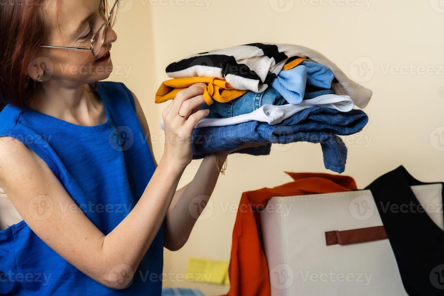 A woman holding a pile of folded clothes with a palette of calm and bright colors as part of a minimalist wardrobe experiment using color psychology to inspire mood and daily outfit choice photo