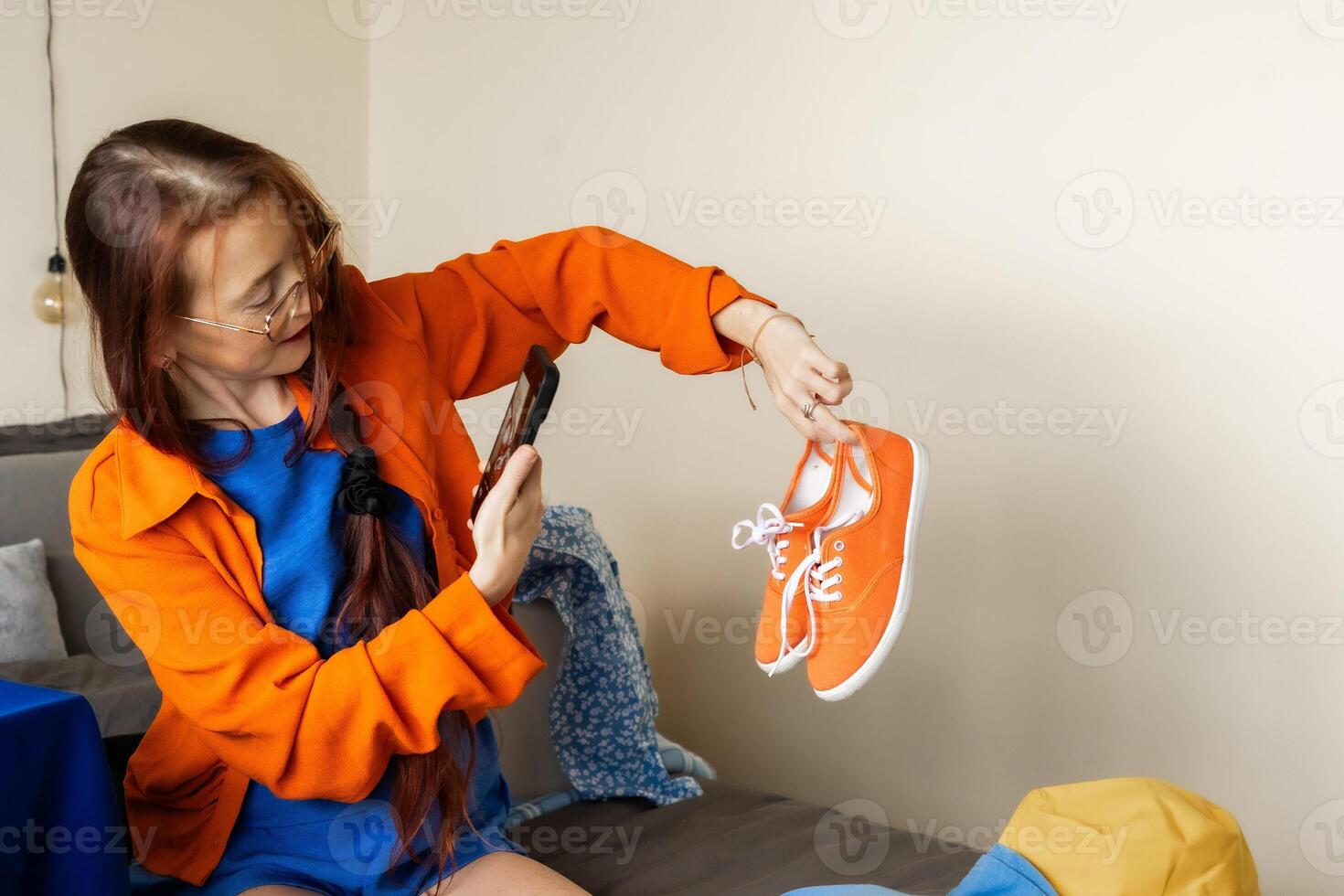 A woman documents her decluttering journey by photographing bright sneakers for online resale while embracing a conscious lifestyle through visual storytelling, digital minimalism and self-branding photo