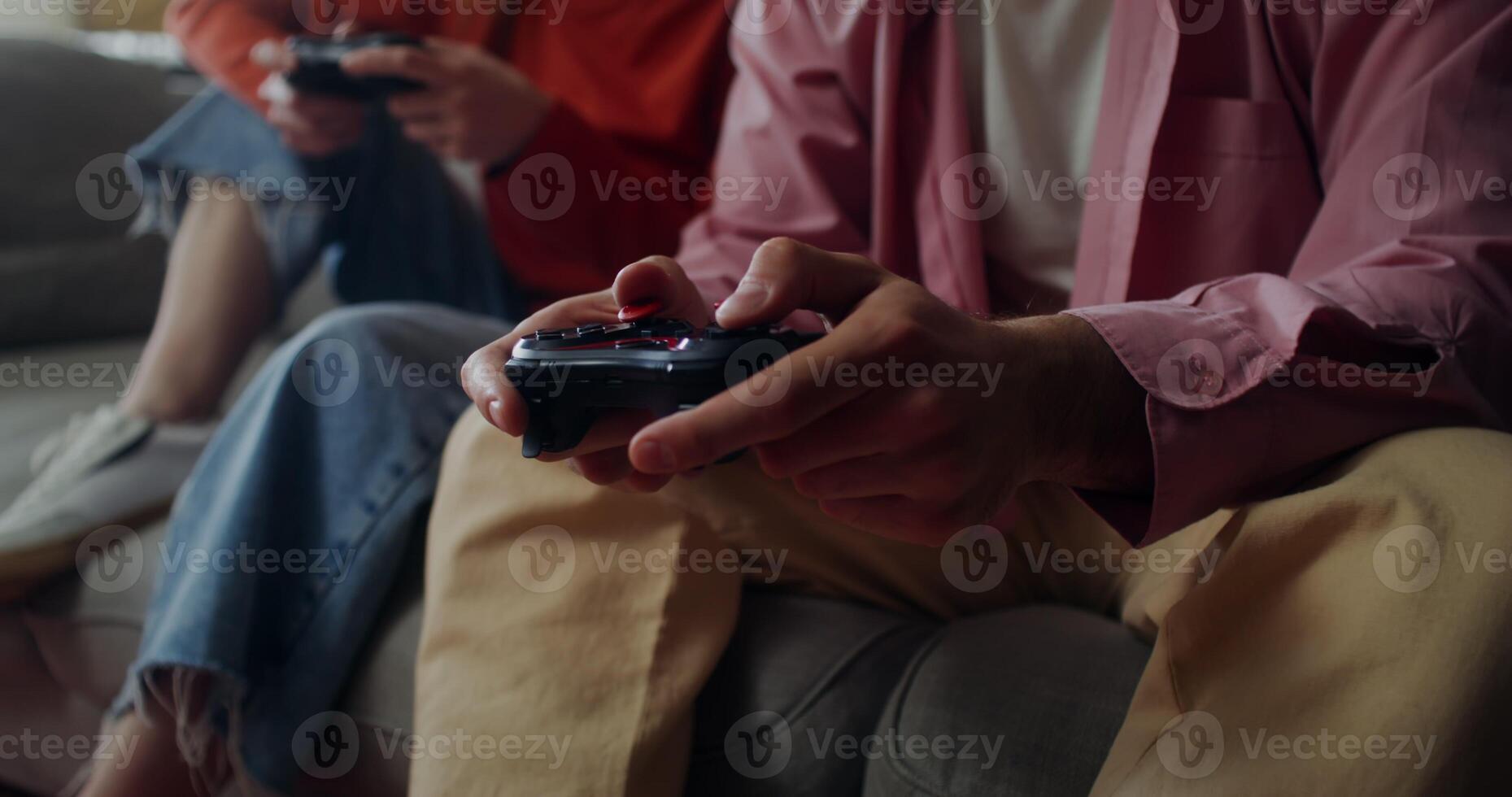 A man and a woman play games while sitting on the couch at home. Close-up of male hands with a joystick, no face photo