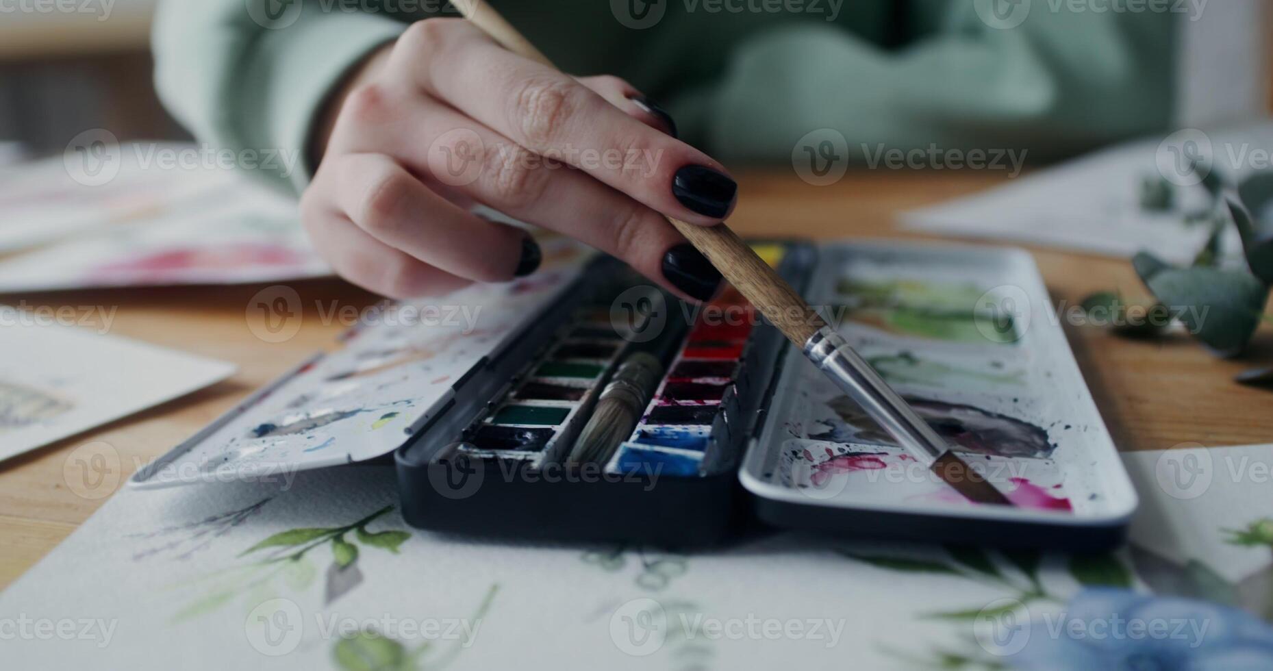A woman artist mixes watercolor paints with a brush photo