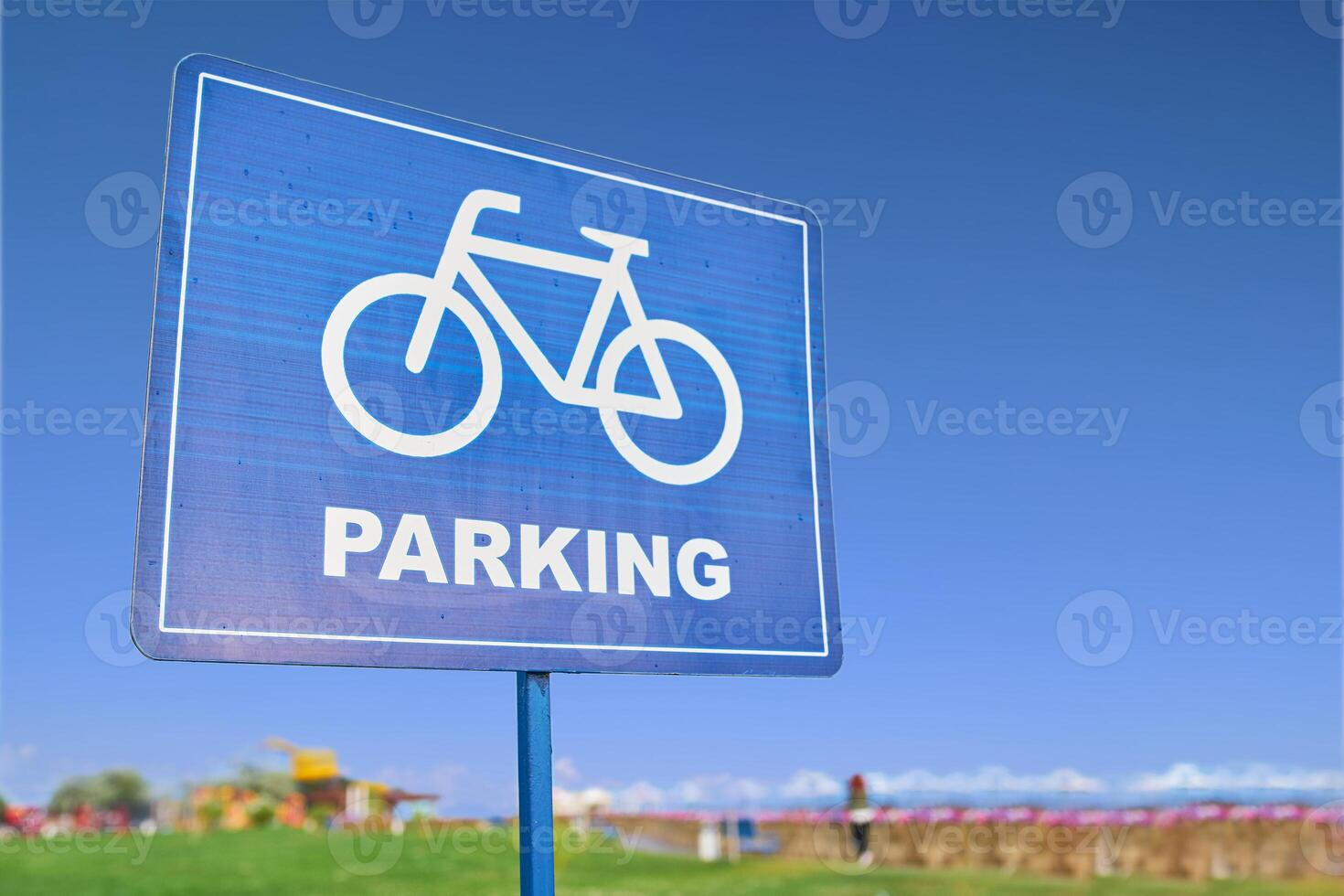 A blue traffic sign featuring a bicycle symbol against a backdrop of the sky, grass, and plants. The font is bold and easy to read, emphasizing the importance of sharing the road with bicyclists photo