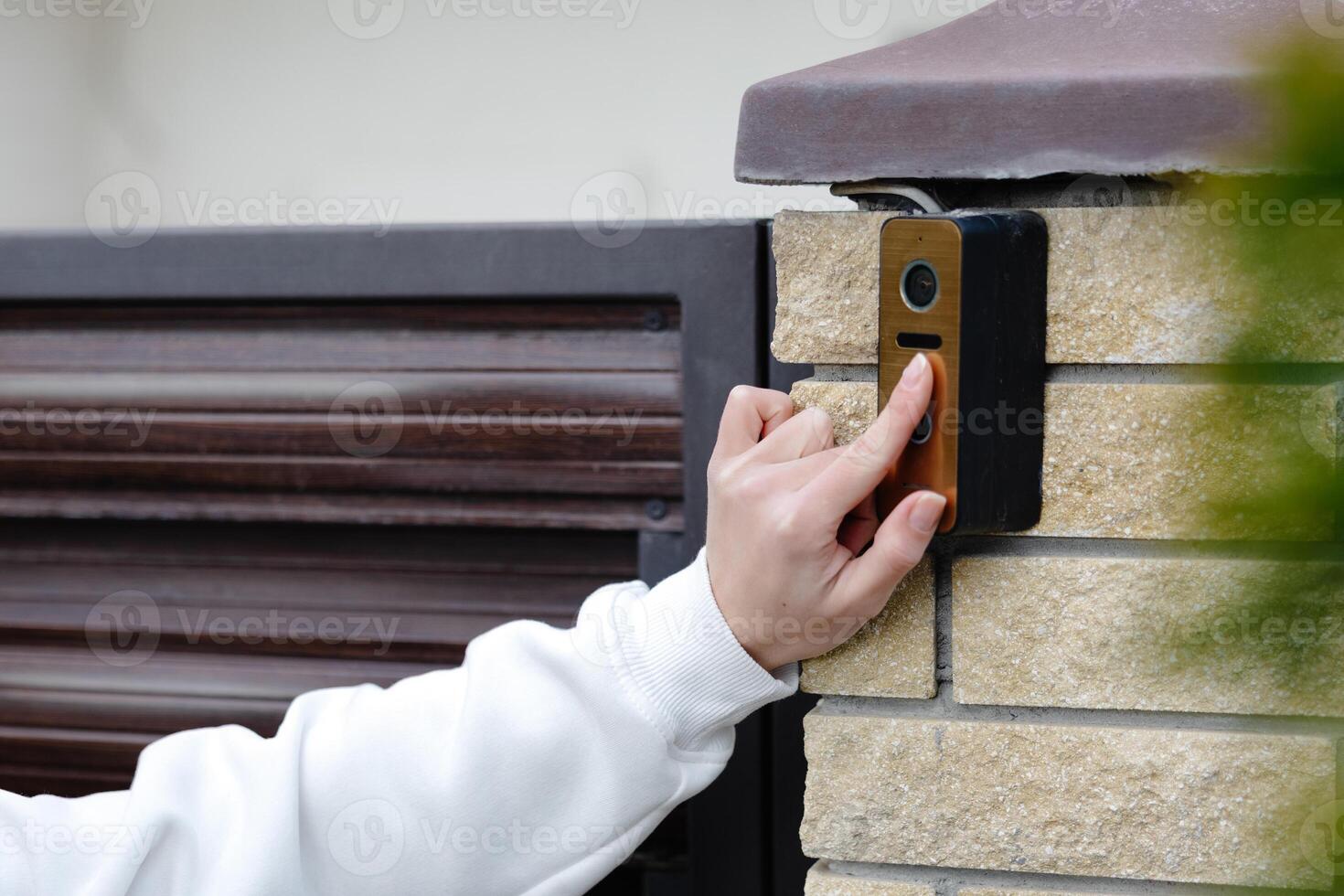 Woman pressing button on modern intercom system at building entrance photo