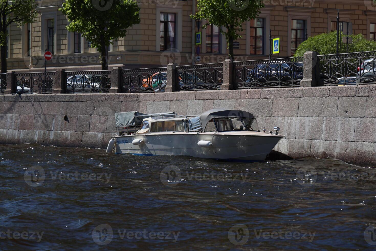 A Serene Boat Floating Gently by the Riverbank in an Urban Setting with Scenic Views photo