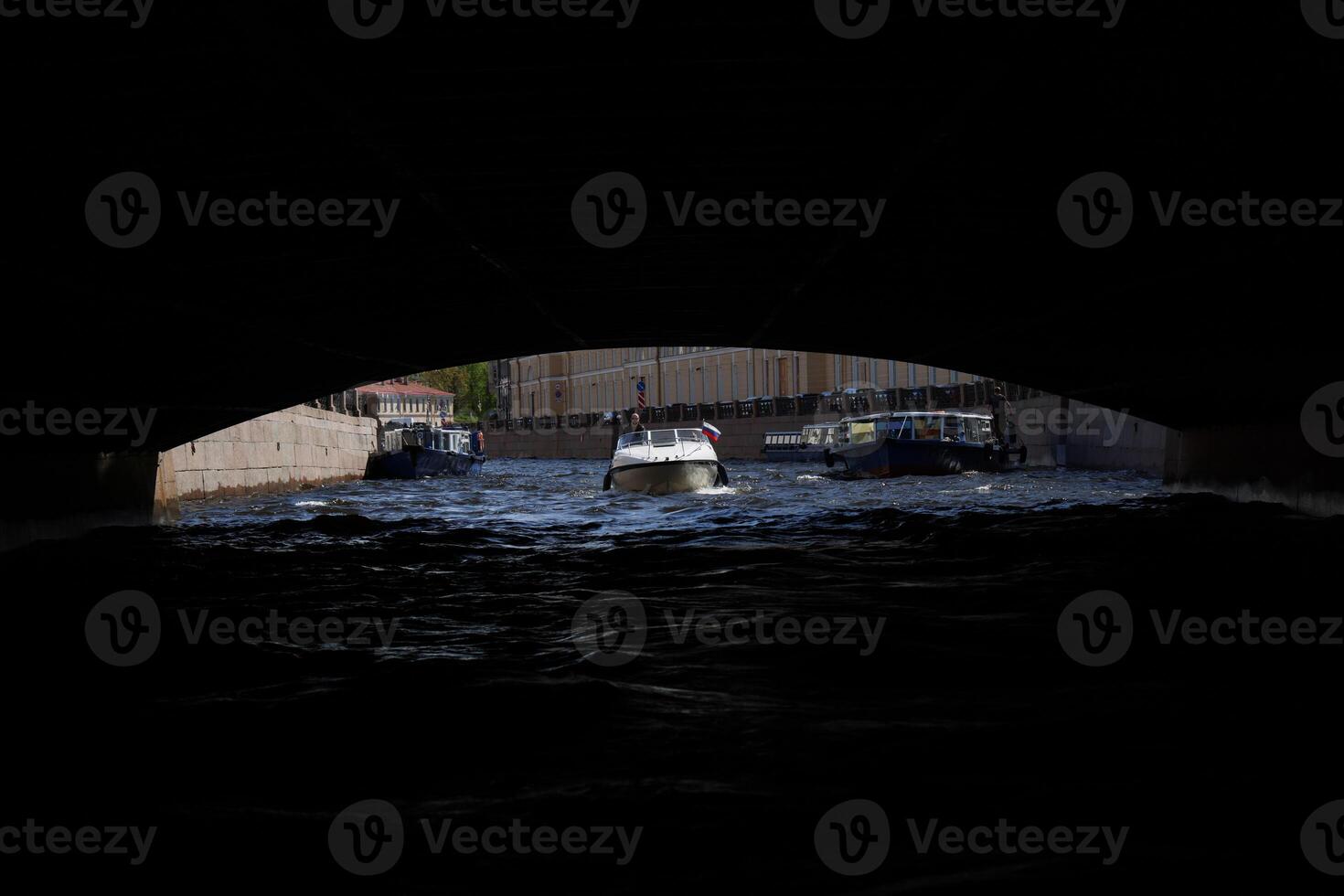 Boats gracefully glide through an archway as they navigate the calm, serene waters ahead photo