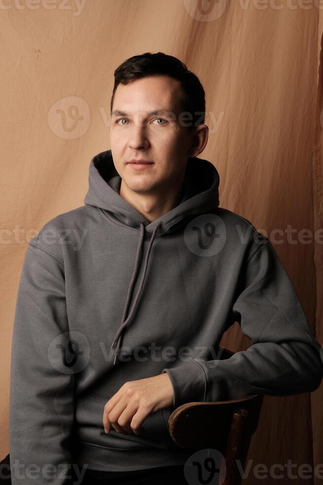 A Casual Portrait Depicting a Young Male Dressed in a Stylish Hoodie in a Studio Environment photo