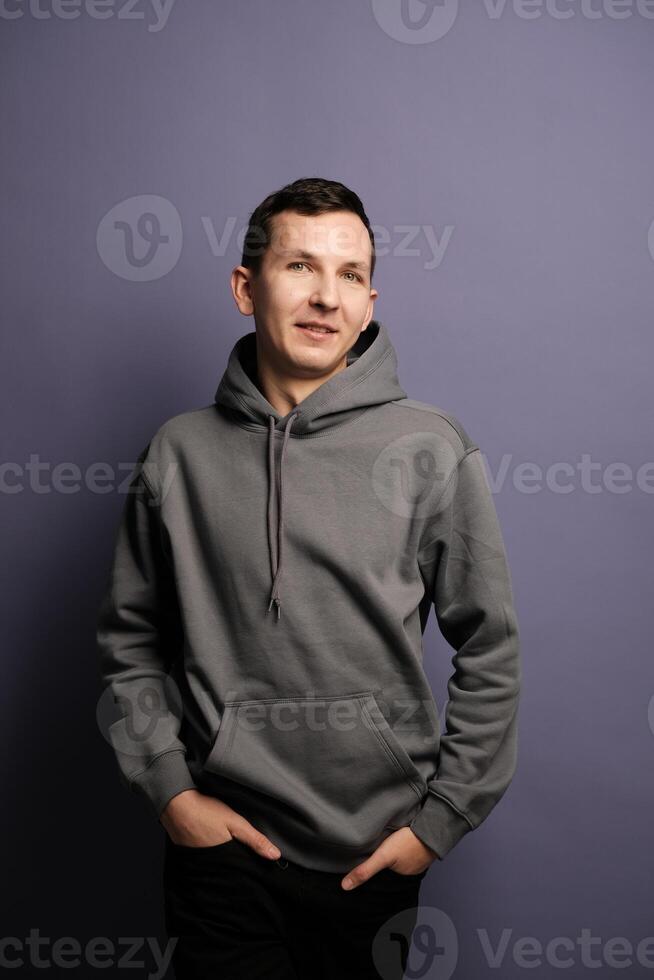 A Casual Portrait Featuring a Man Dressed in a Gray Hoodie Set Against a Vibrant Purple Background photo