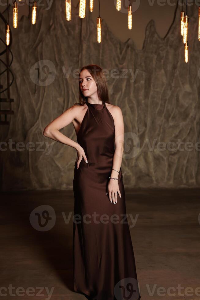 An Elegant Fashion Model Posing Gracefully in a Beautiful Brown Dress within an Artistic Setting photo