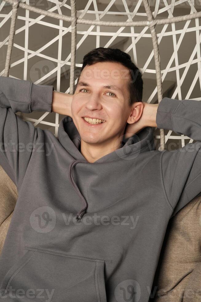 A Happy Young Man is Seen Relaxing Comfortably on His Cozy Sofa in a Bright Setting photo