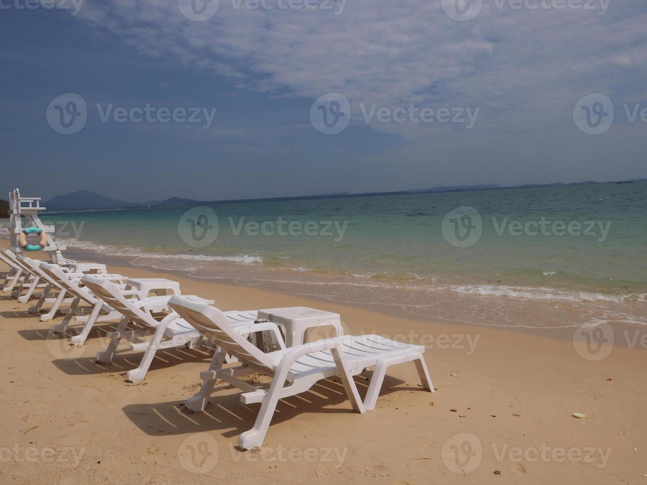 Experience the beauty of a serene beachfront complete with lounge chairs and crystal clear waters photo