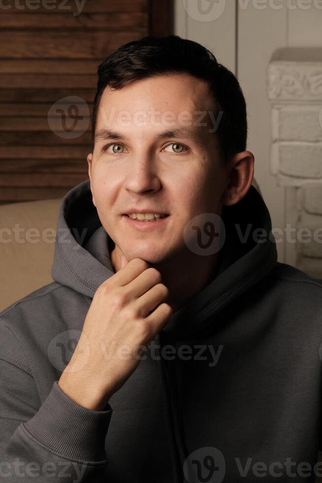 A curious and contemplative young man dressed in casual attire, surrounded by a cozy atmosphere photo