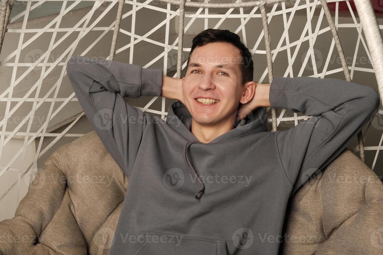 A man is sitting comfortably in a modern chair, exuding joy and radiating a cool, relaxed attitude photo
