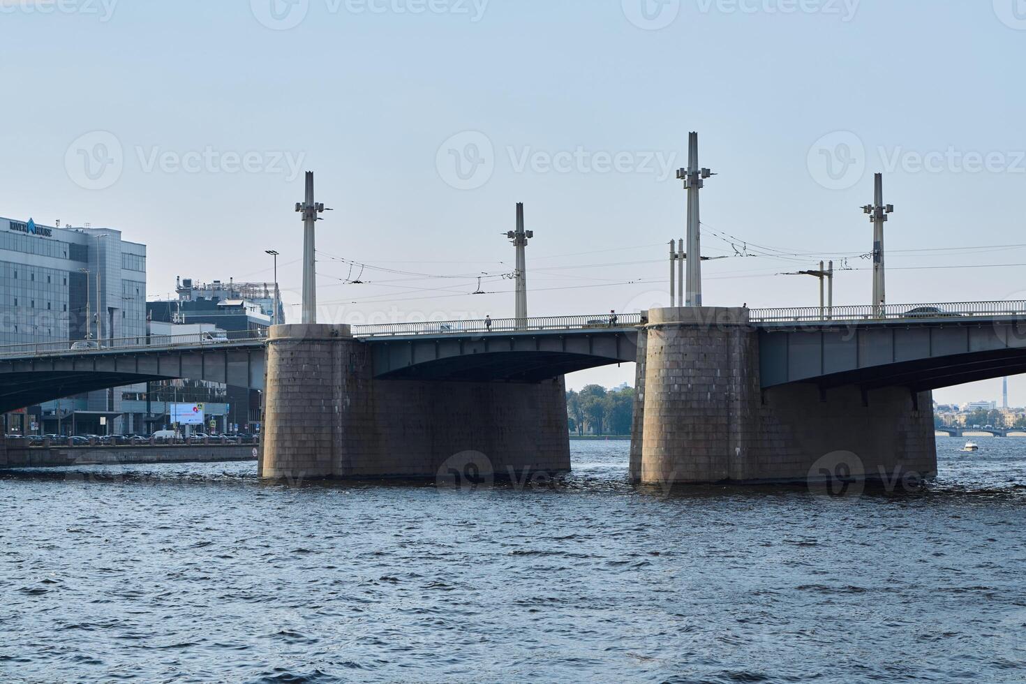 A Contemporary Modern Bridge Spanning Over Water with a Vibrant Urban City Background photo