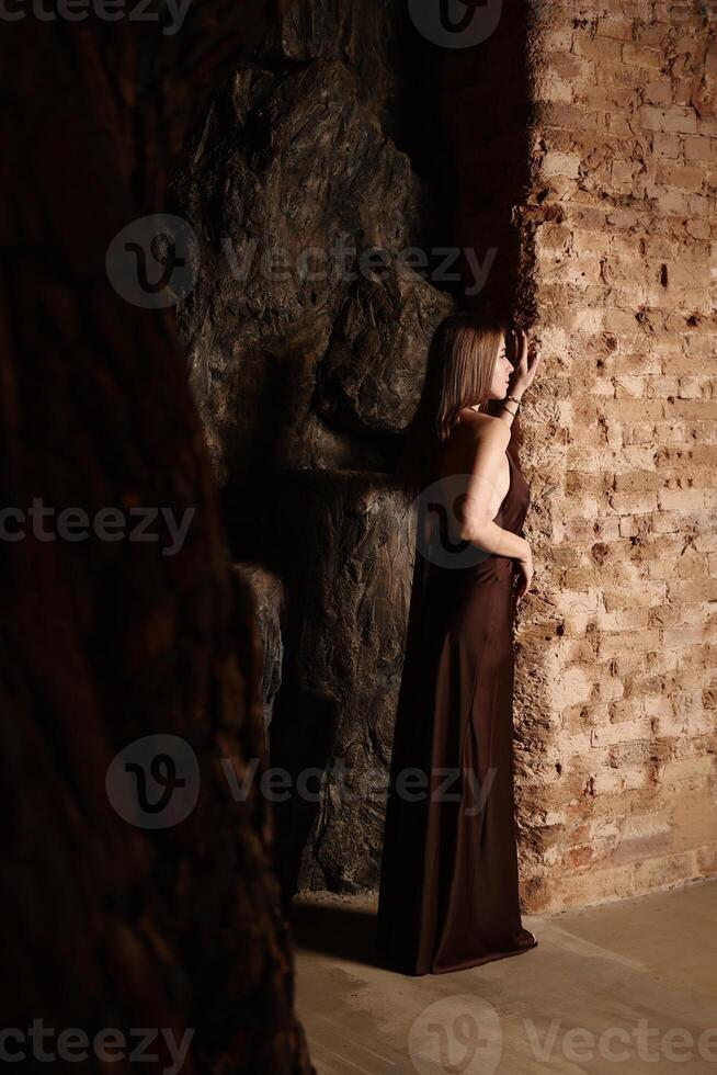 A Sophisticated and Elegant Woman Posing Gracefully in a Dimly Lit Architectural Space photo