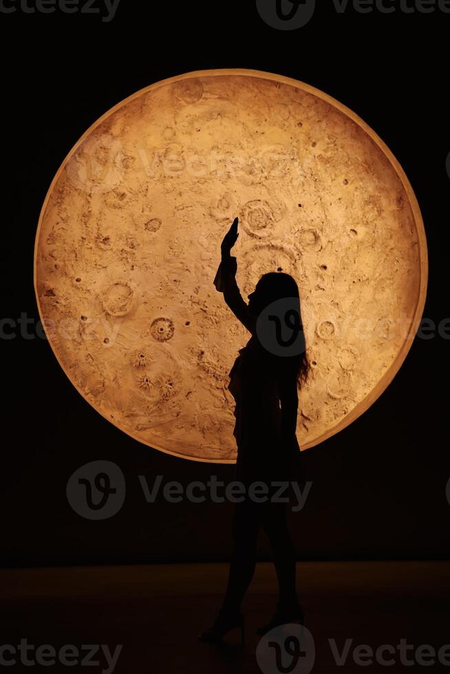 A striking silhouette set against a large, moonlike sphere creates a captivating visual photo