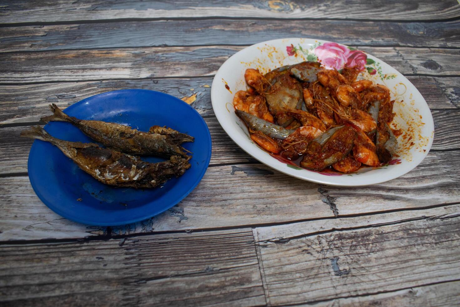 Freshly fried chili prawns and fish are placed on a plate, ready for a delicious seafood meal. photo