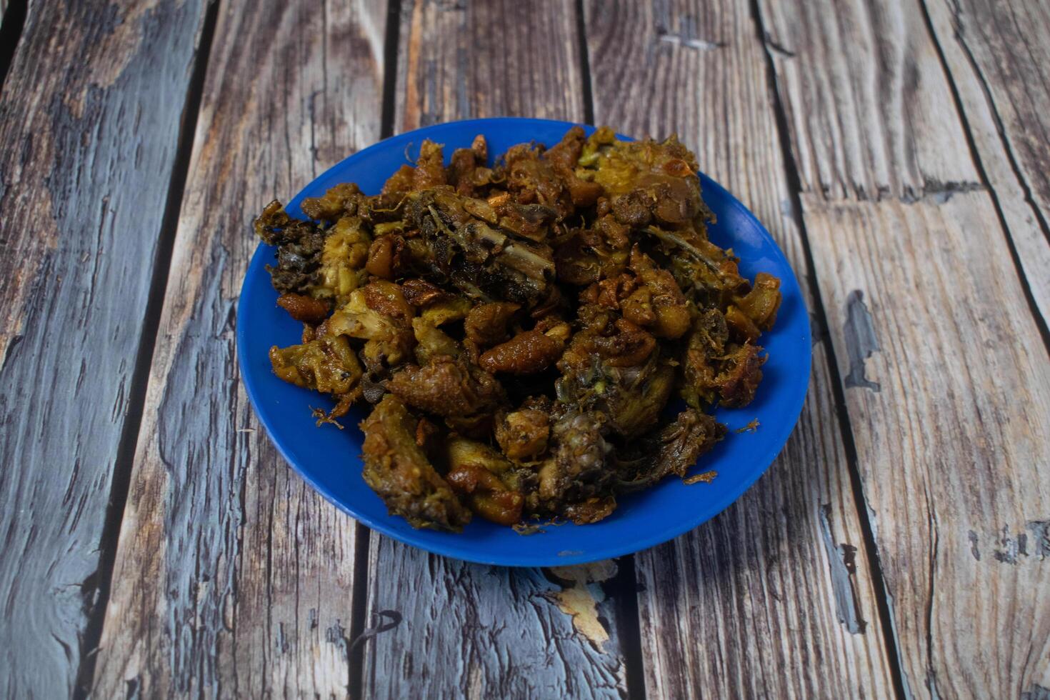 A blue plate filled with crispy fried chicken skin, served on a rustic wooden surface. photo