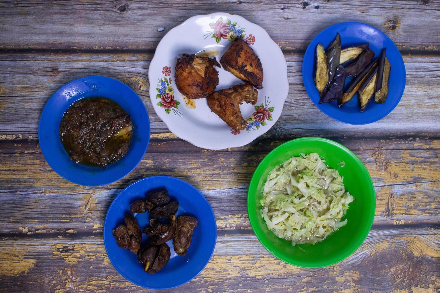 Delicious local cuisine served on vibrant plates, featuring vegetables, meats, and sambal. photo