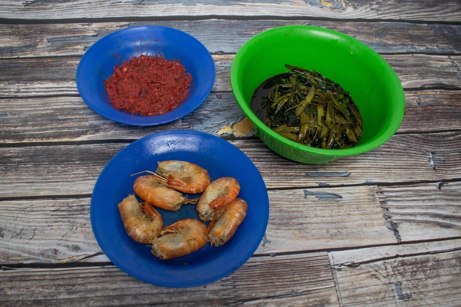 Delicious shrimp, stir-fried vegetables on blue and green plates on a wooden table. photo