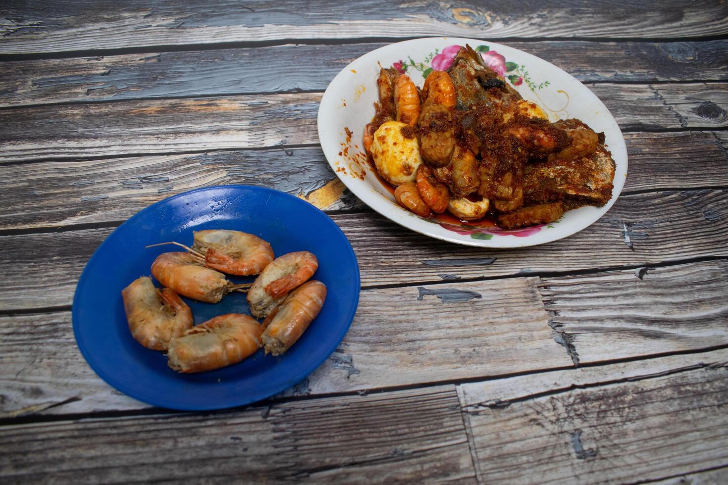 A spicy food plate containing fried eggs, shrimp, fish and prawns. photo