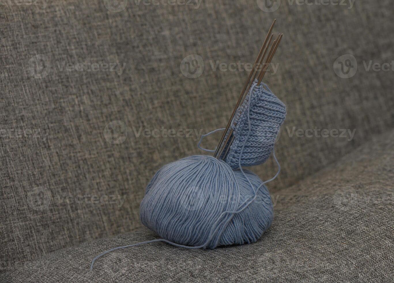 Composition with a yarn ball, knitting needles, and the beginning of a sock on a wooden surface. photo
