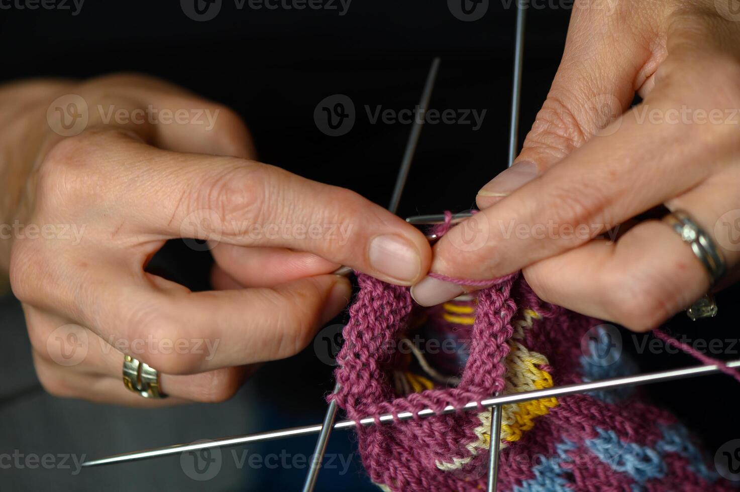 Close-up of a woman knitting colorful patterned socks by hand. Artistic handmade craft in daylight. photo