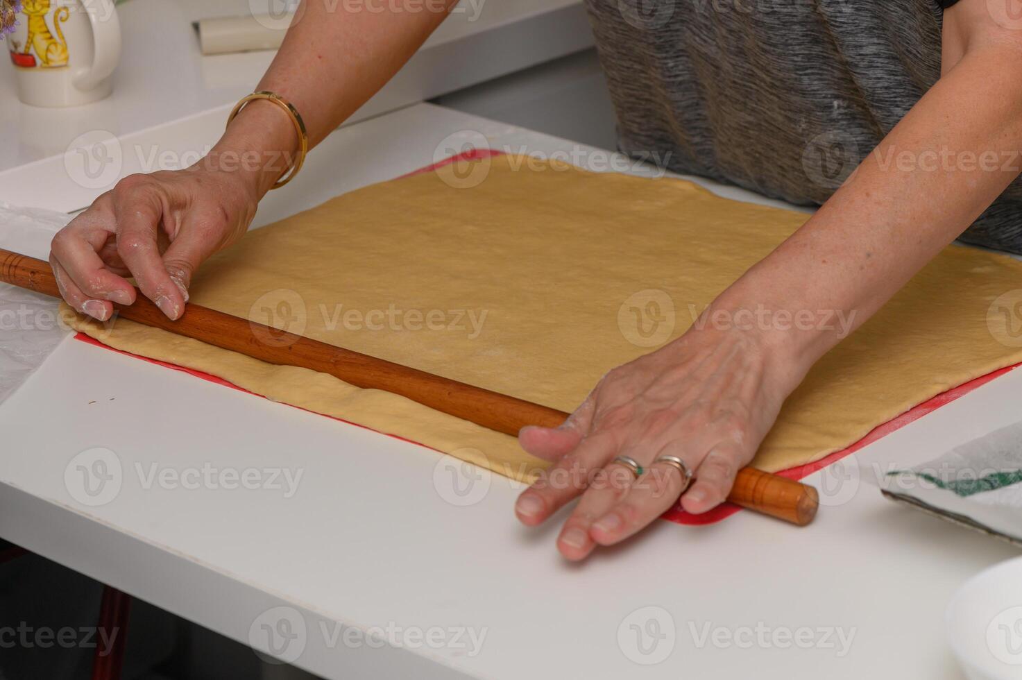 Woman Rolling Out Dough for Homemade Pastries on Floured Surface photo