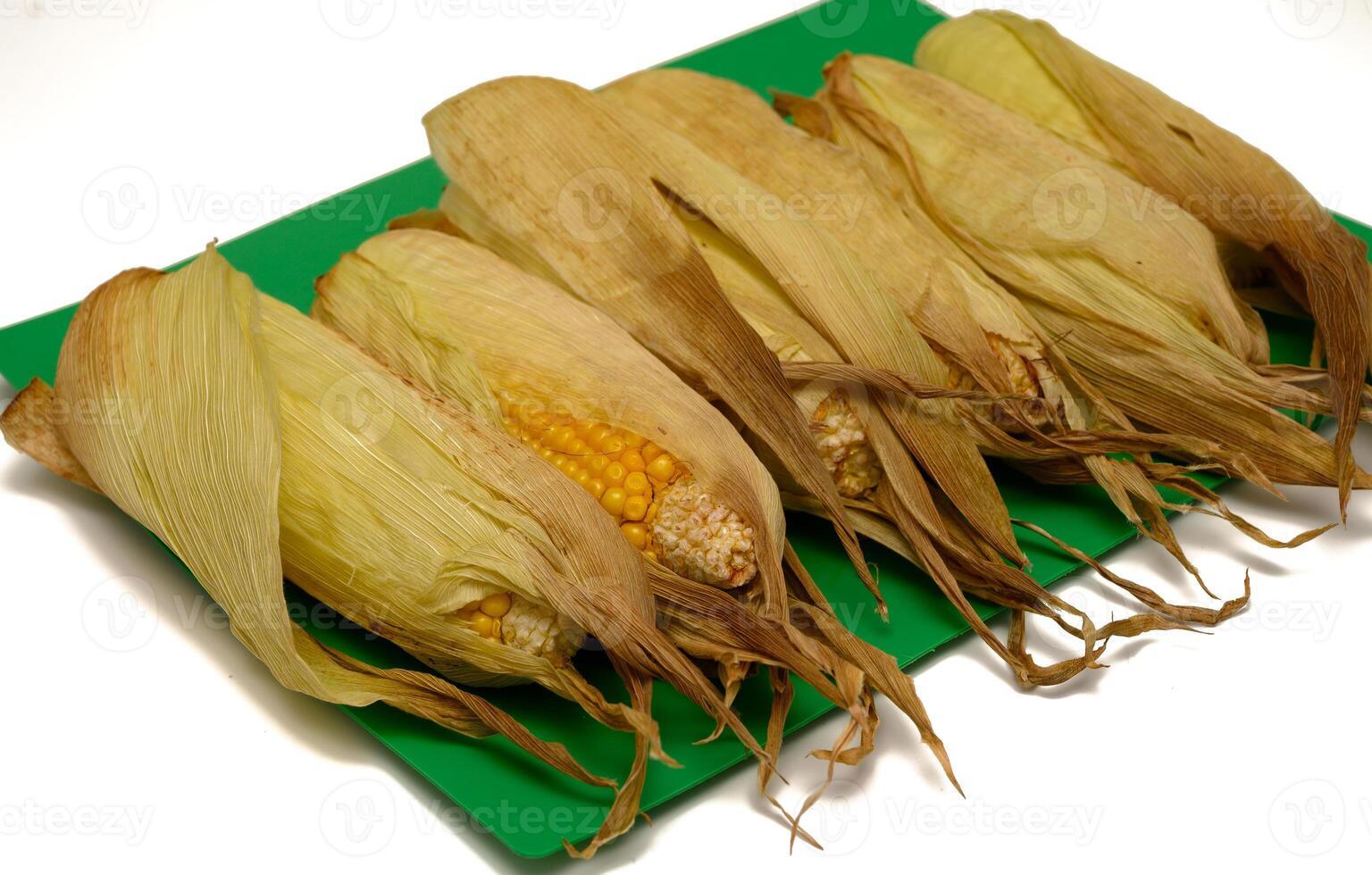 Golden baked corn on the cob arranged on a white background. Healthy, rustic snack or side dish. photo