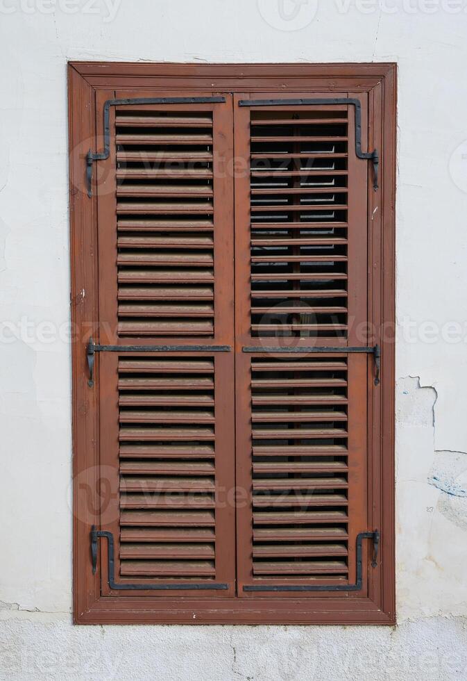 Close-up of a rustic window with classic wooden shutters on a traditional house in Cyprus. photo