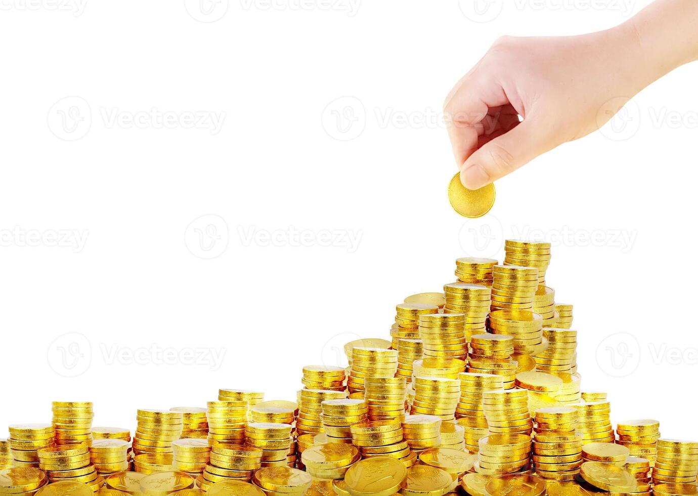 Image of a gold coin in hand and a pile of gold coins. photo