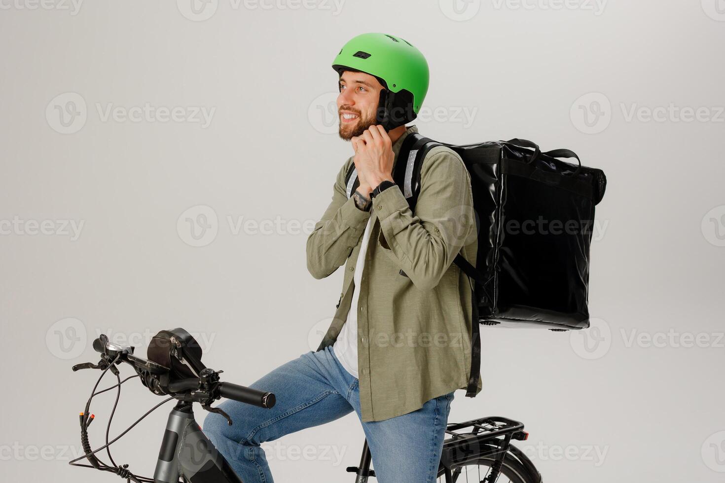 Delivery rider prepares for work while sitting on bicycle with backpack full of orders in studio setting photo