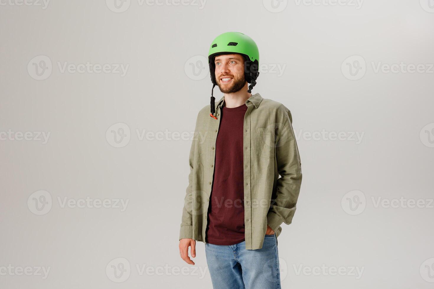 Individual stands confidently in casual attire and a vibrant green helmet against a plain background, exuding readiness for adventure photo