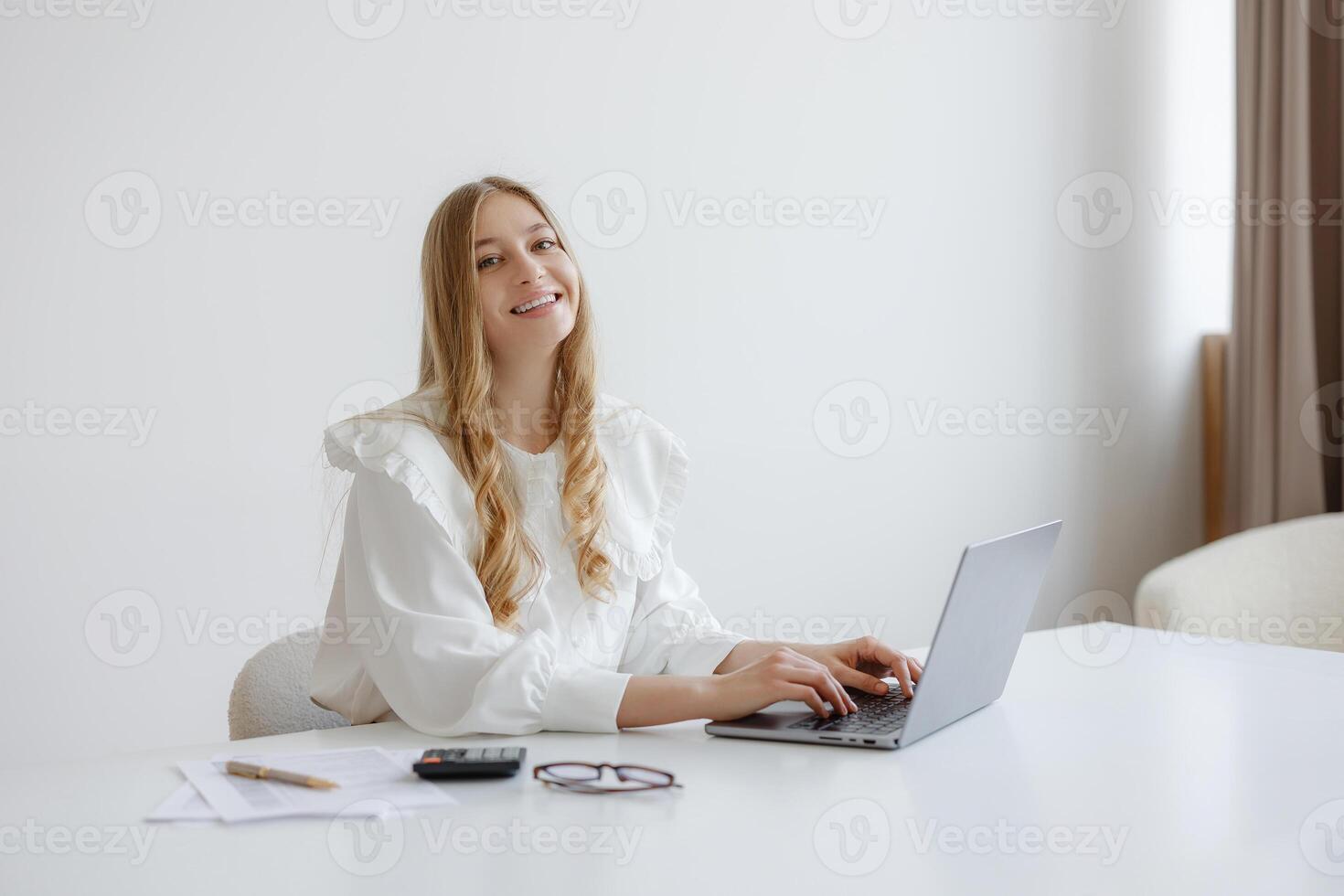 Young woman working on laptop in bright modern workspace during daytime photo