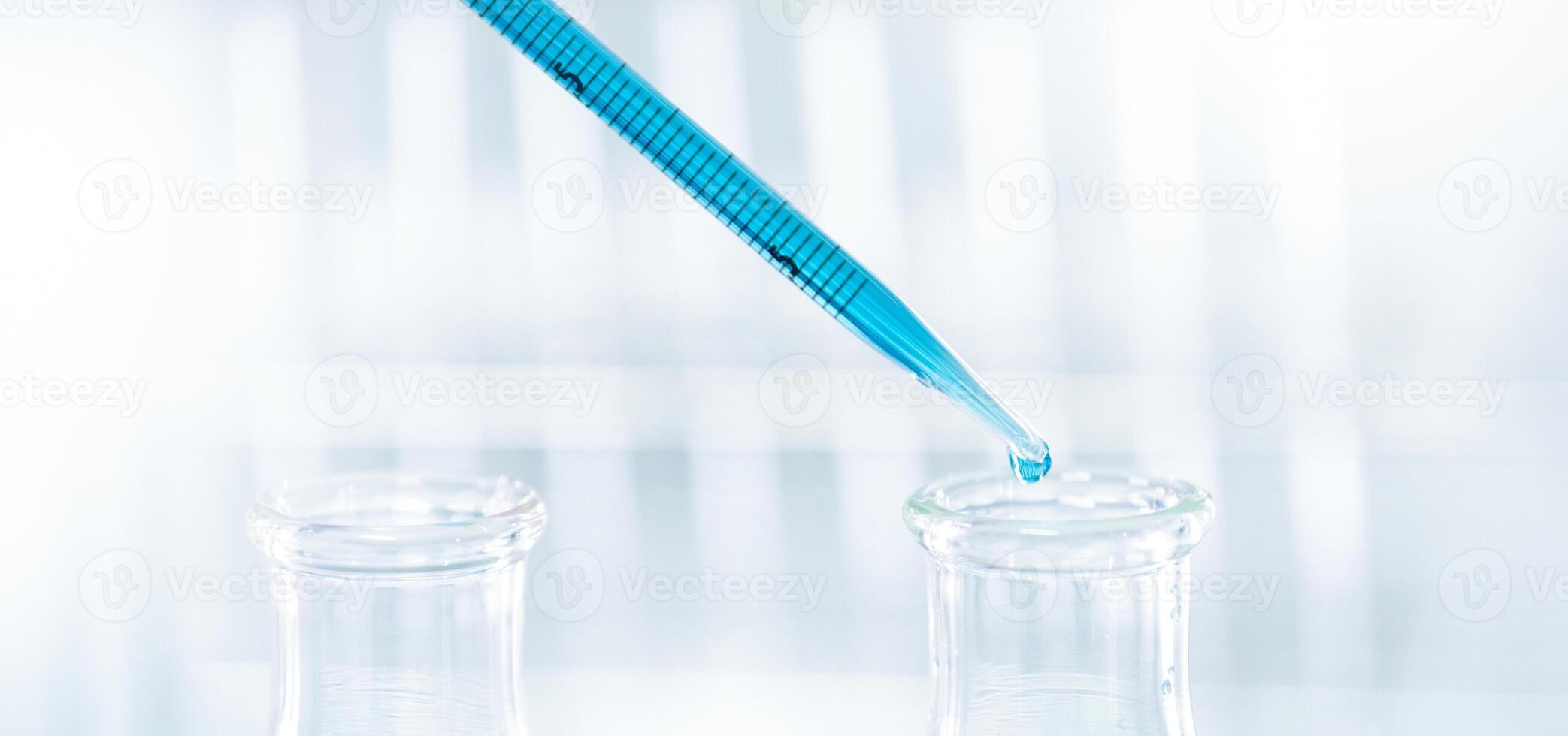 Doctor or scientist using pipette to drop a sample to test tube in medical research lab photo