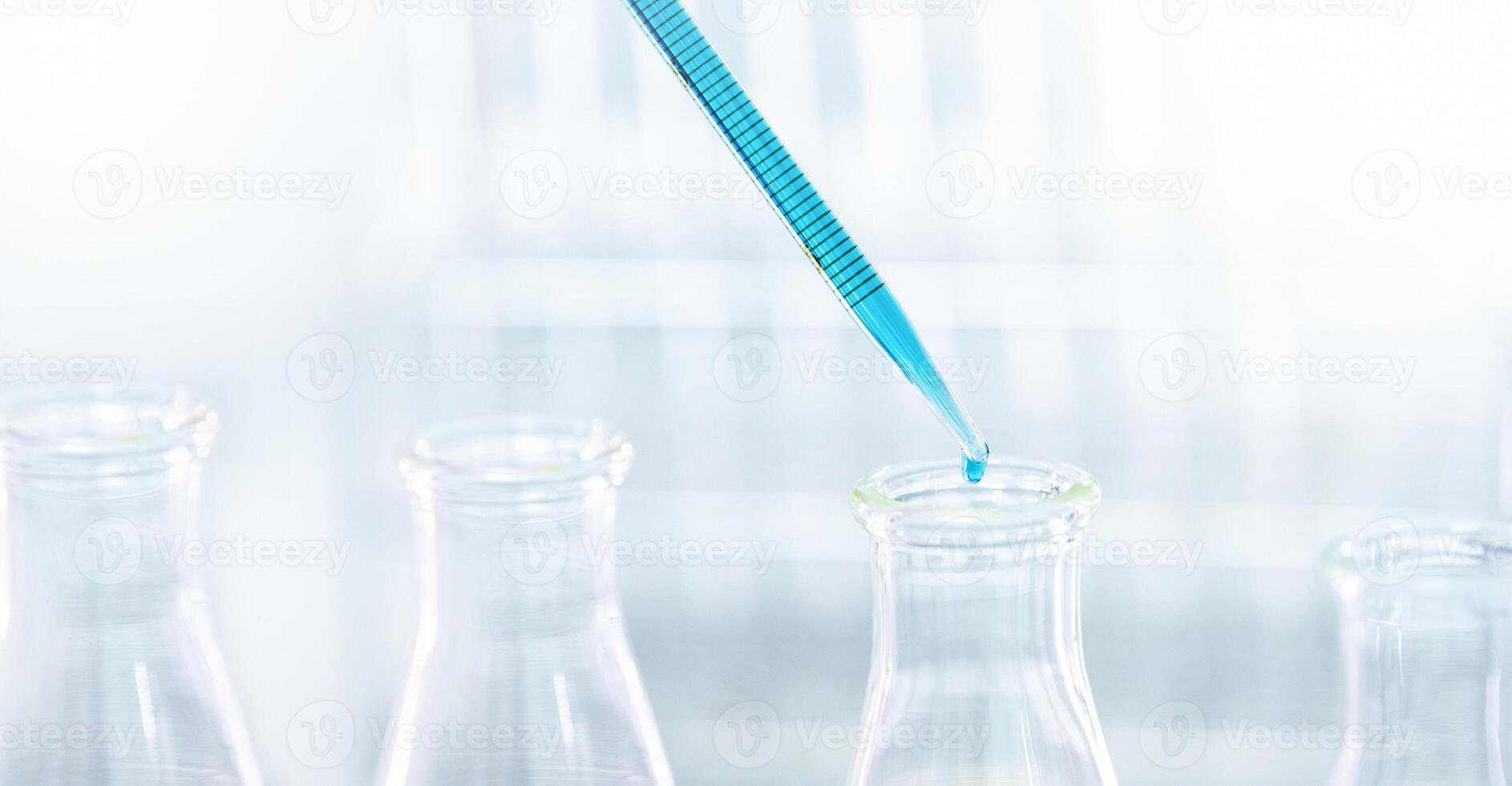 Doctor or scientist using pipette to drop a sample to test tube in medical research photo