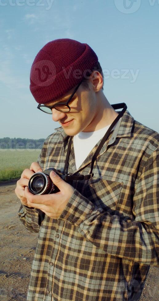 A young man takes photographs with a camera while standing on a gravel road photo