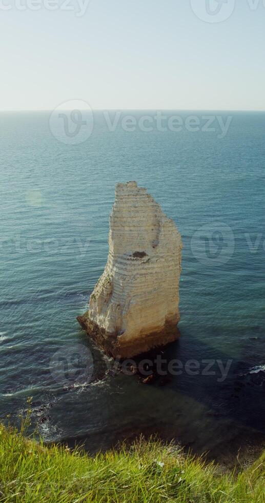 Detached limestone peak sticks out of the sea water, not far from the coast. Top view from the top of the hill. Etretat, France. 4k vertical , red komodo photo