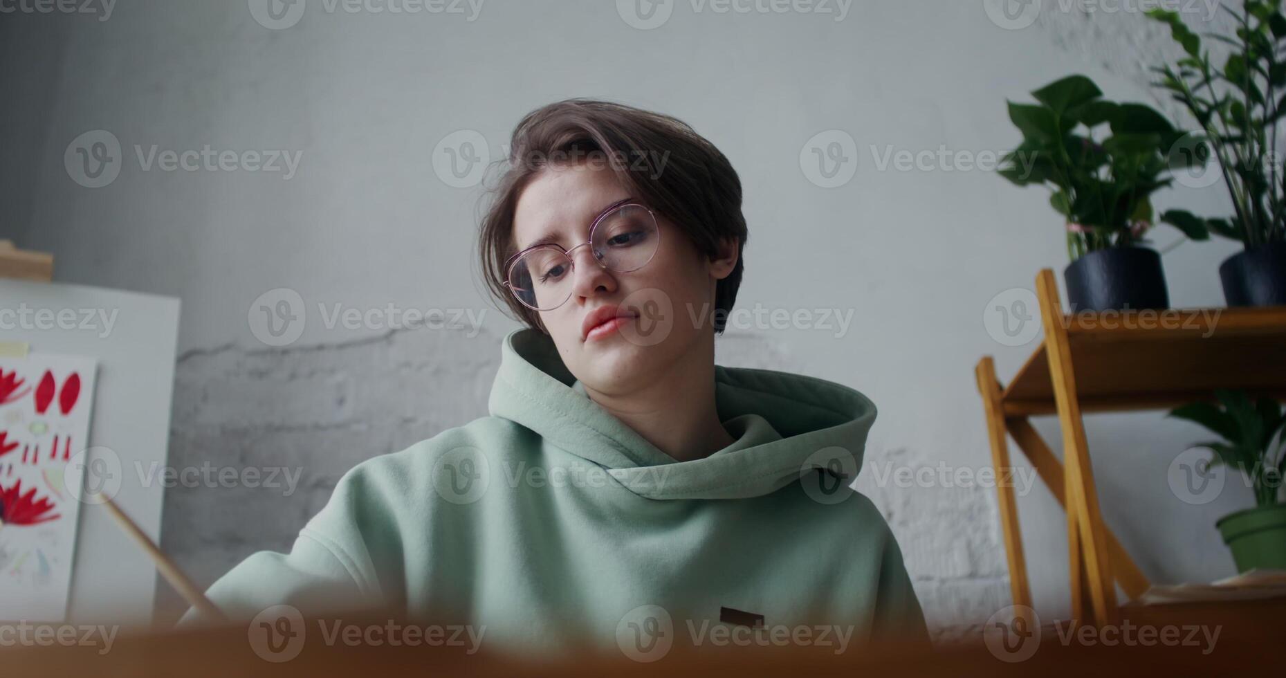 A young woman in glasses draws with paints photo