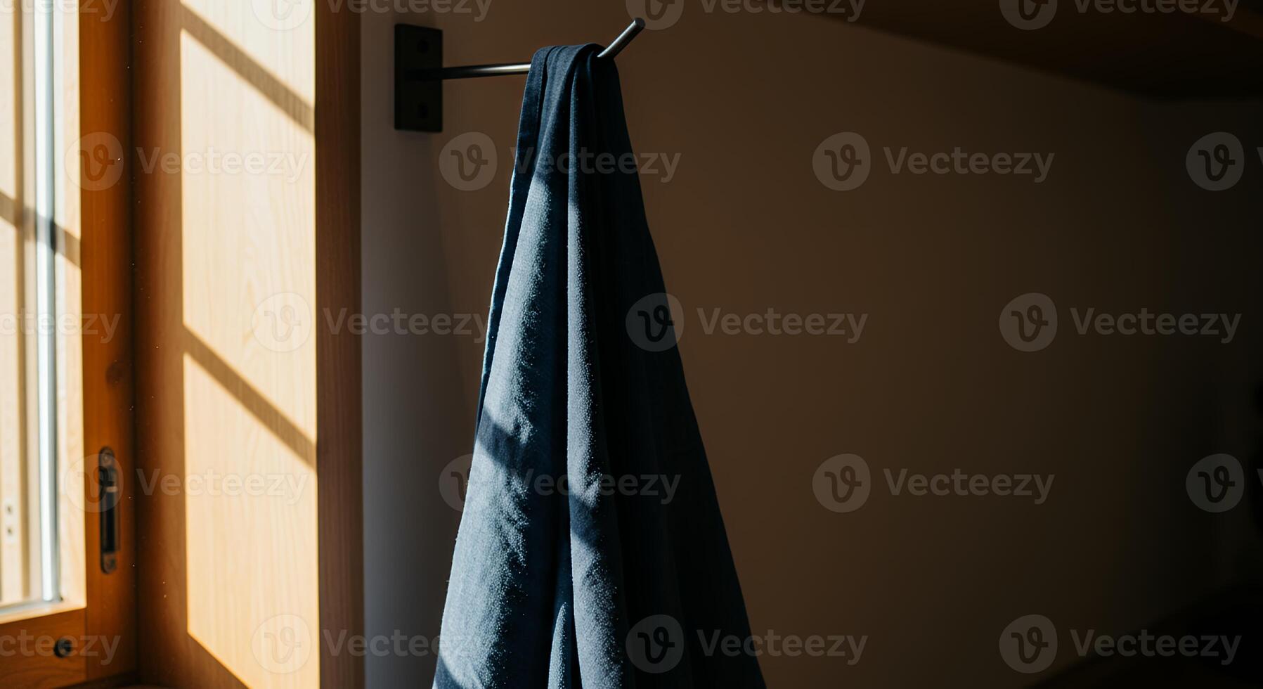 A blue towel hanging on a hook in front of a window photo