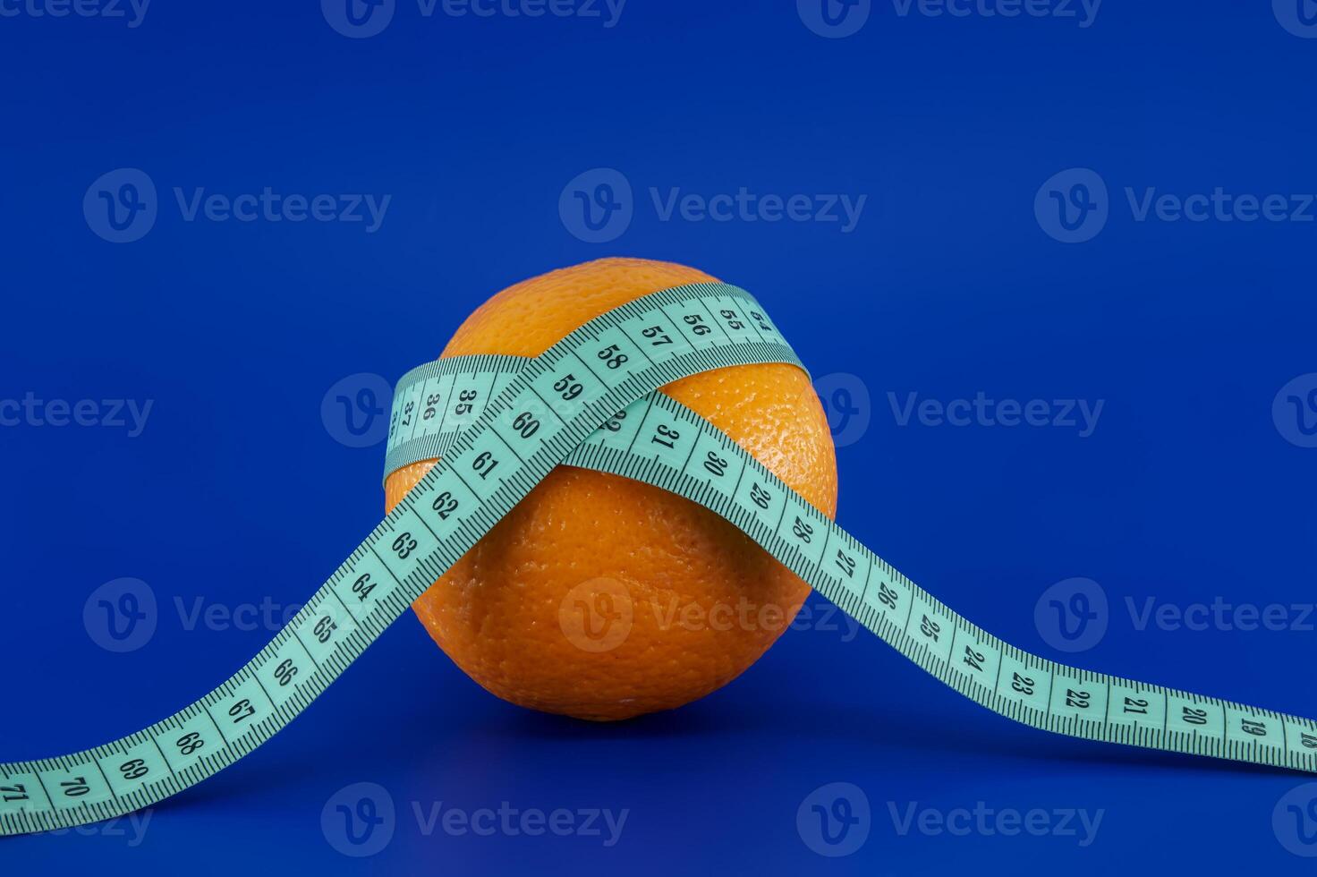 Orange wrapped with a measuring tape, representing diet and weight loss. photo