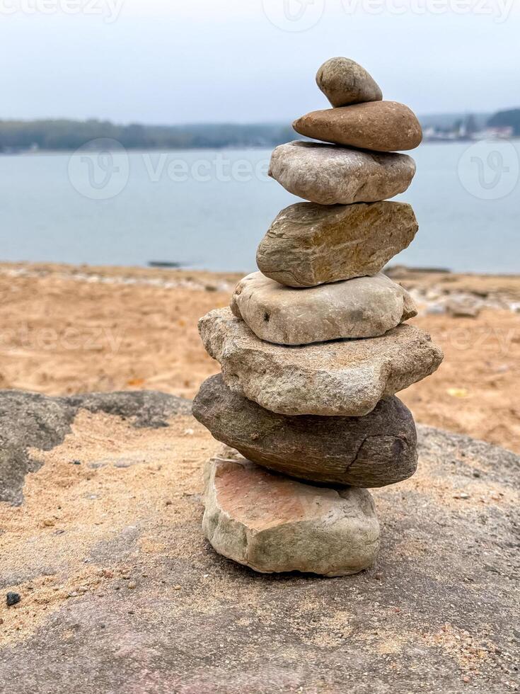 A stack of rocks on the beach near a body of water photo
