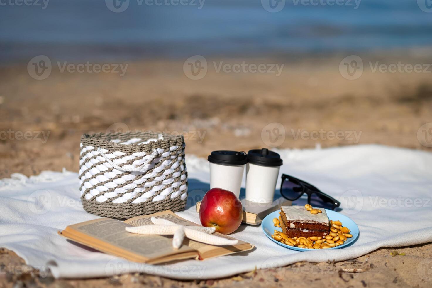 A picnic on the beach with a basket, coffee, and a book photo