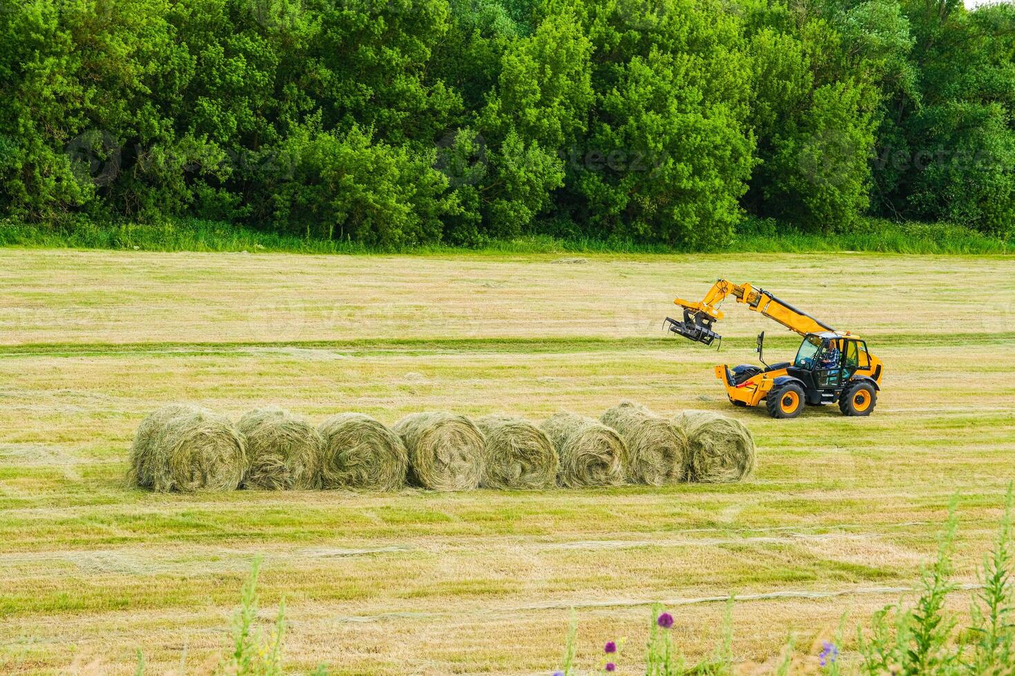a tractor is working on a field with hay bales photo
