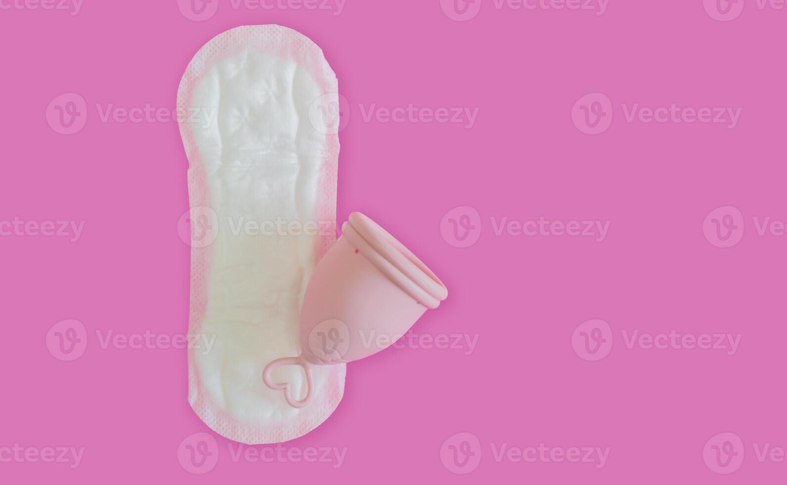 A silicone menstrual cup on the sanitary pad isolate on pink background with copy space. photo