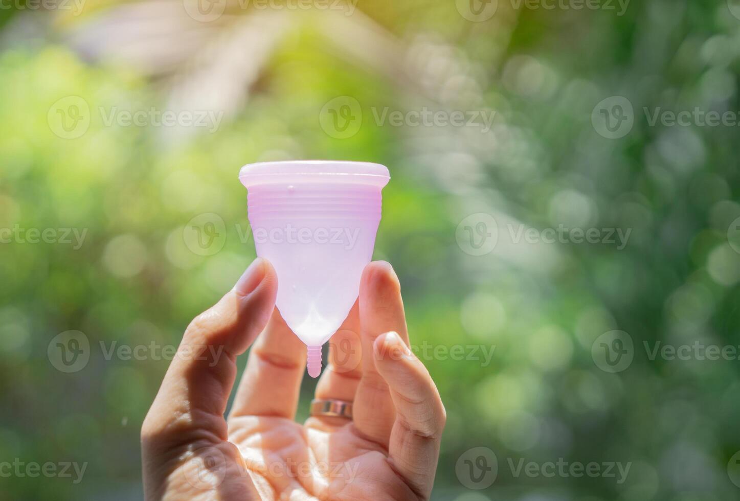 Woman's period, menstrual cup in hands over real nature background, modern methods for crytical days. photo