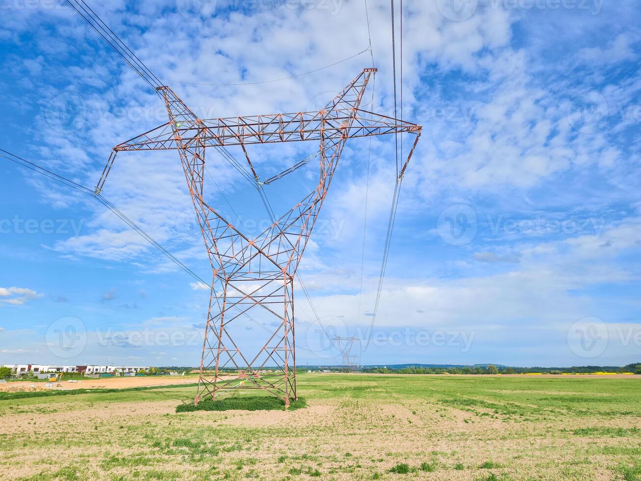 High voltage power lines crossing a field under blue sky photo